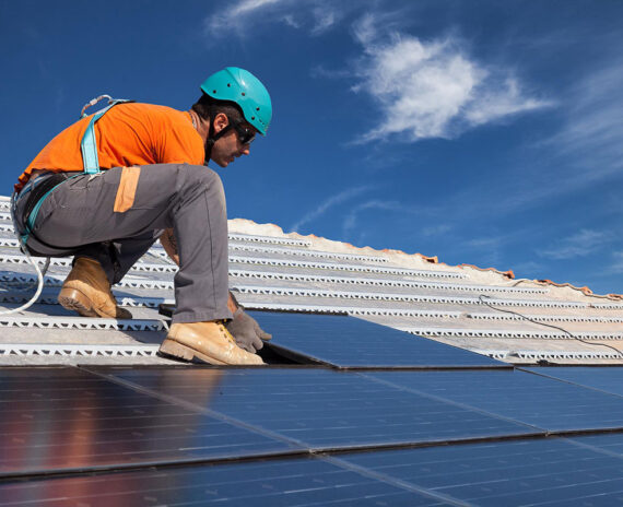 Expert installing photovoltaic panel on rooftop of house.